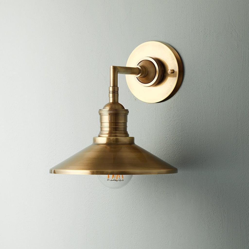 Lyra vägglampa — antik mässing, konformad skärm, synlig glödlampa