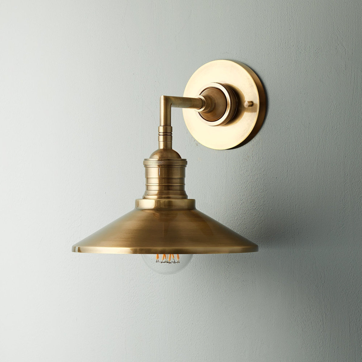 Lyra vägglampa — antik mässing, konformad skärm, synlig glödlampa