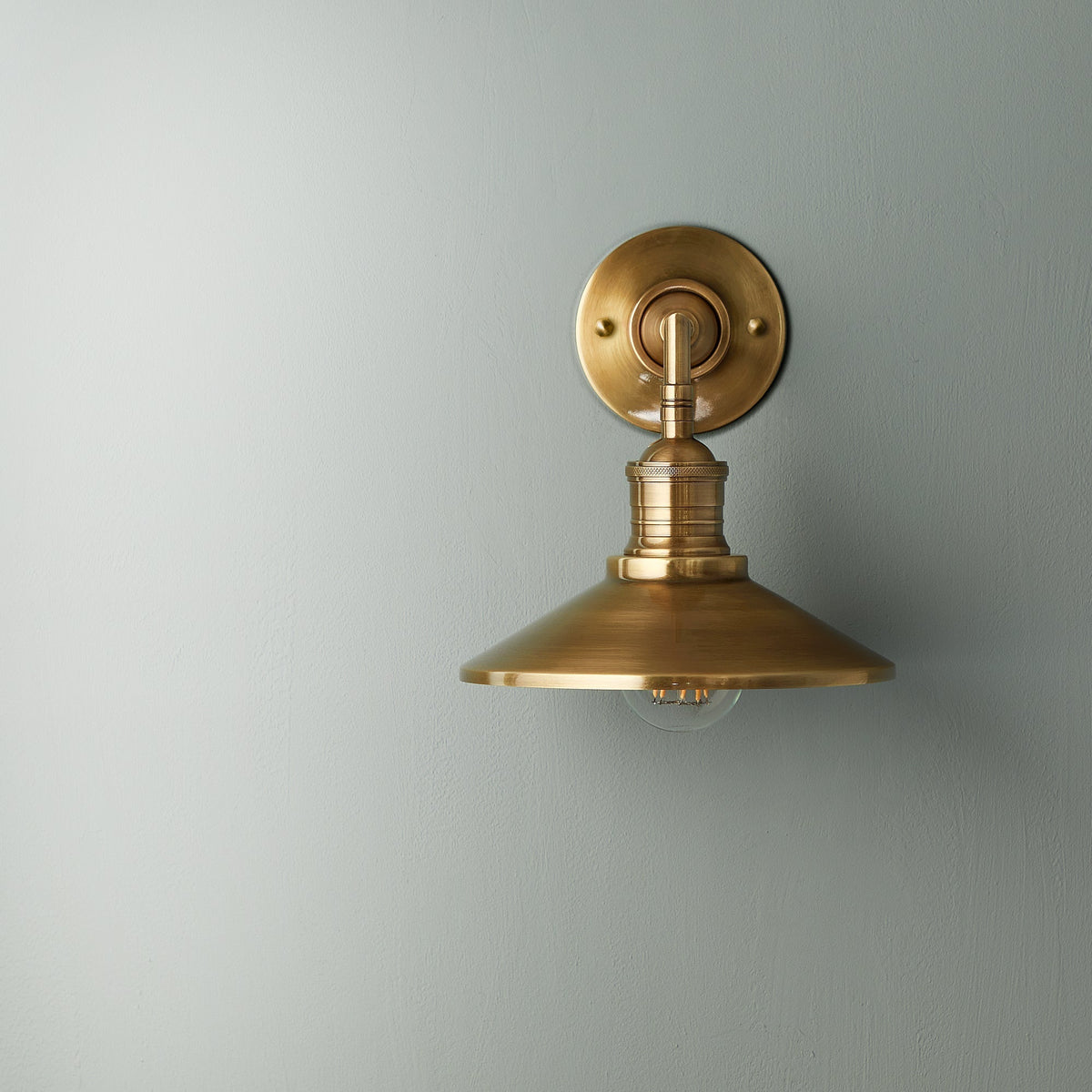Lyra vägglampa — antik mässing, konformad skärm, synlig glödlampa