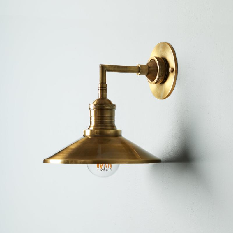Lyra vägglampa — antik mässing, konformad skärm, synlig glödlampa
